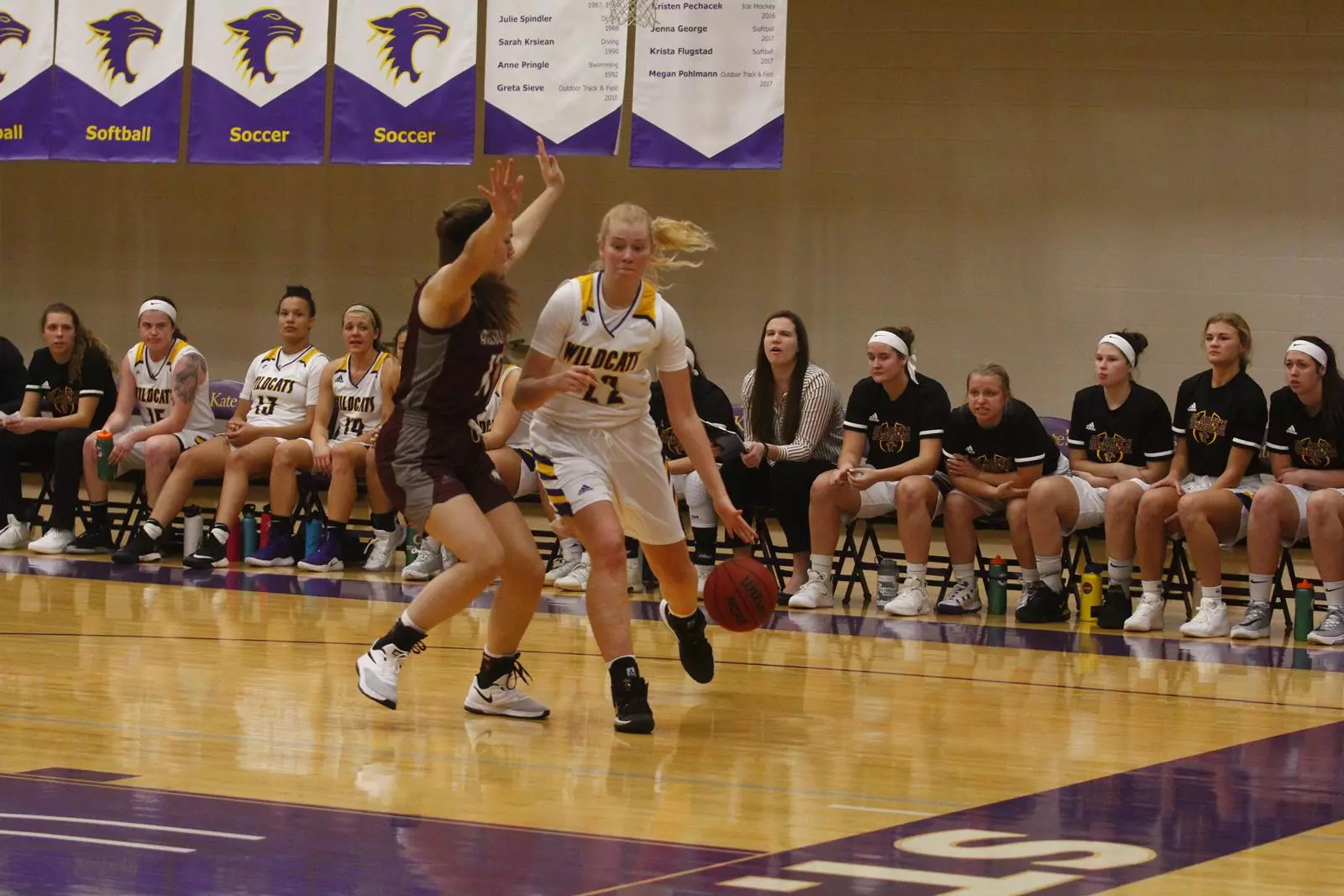 Katie Benjamin dribbiling the ball to the basket with augsburg player defending and wildcat team in the background