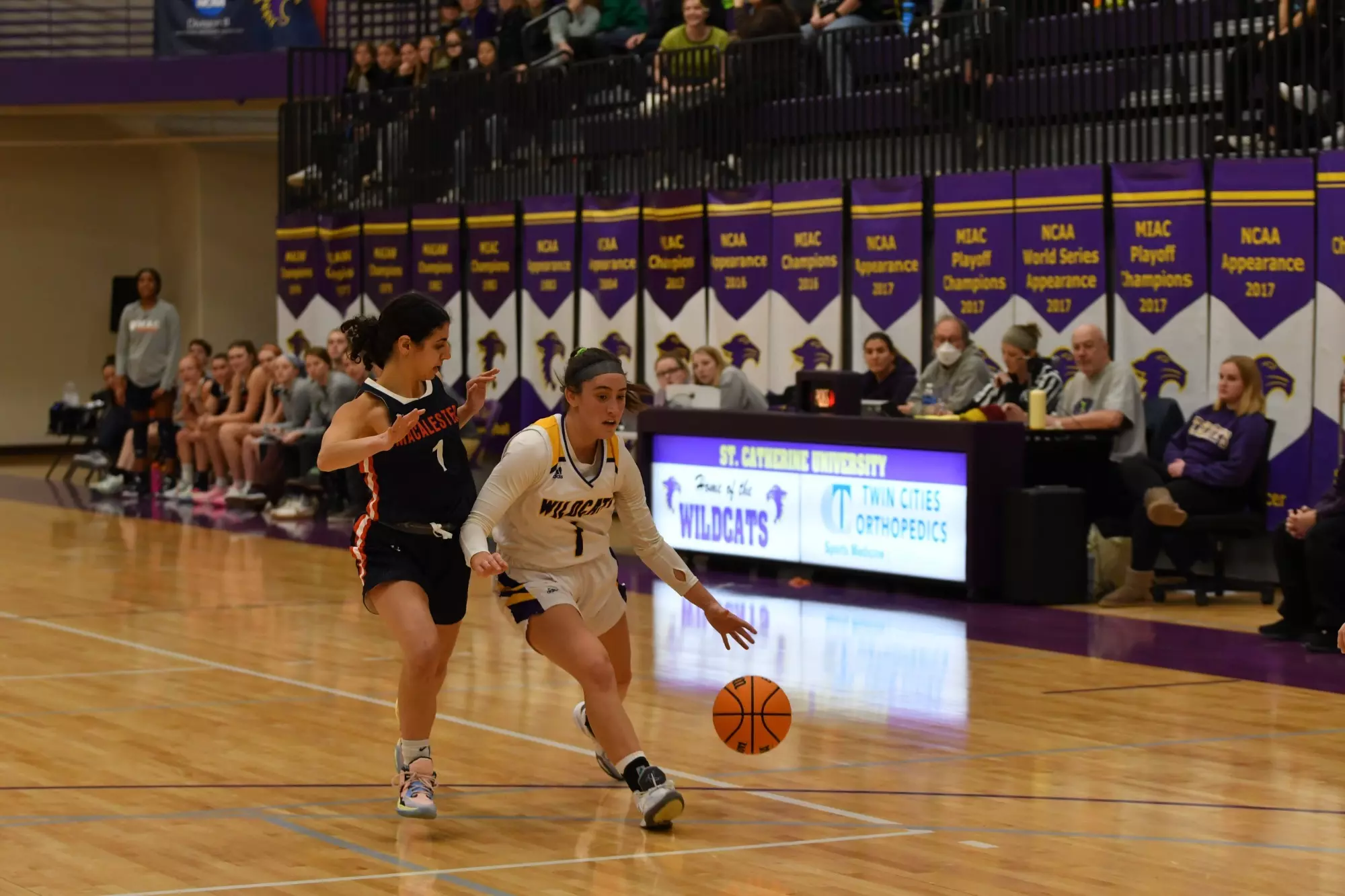 Kaylee Miron dribbling down court with Macalester player
